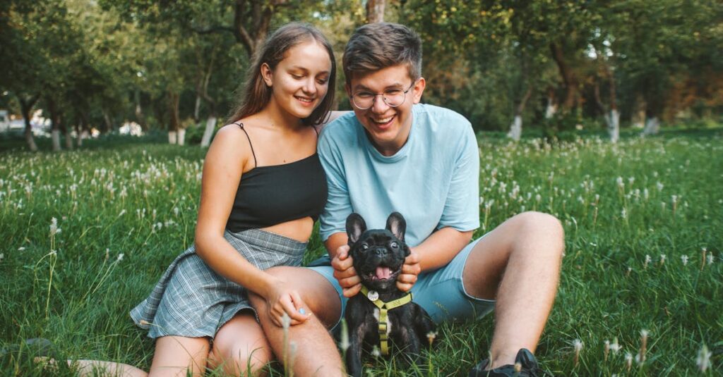 Young couple enjoying a day outdoors with their French Bulldog in a sunny park.